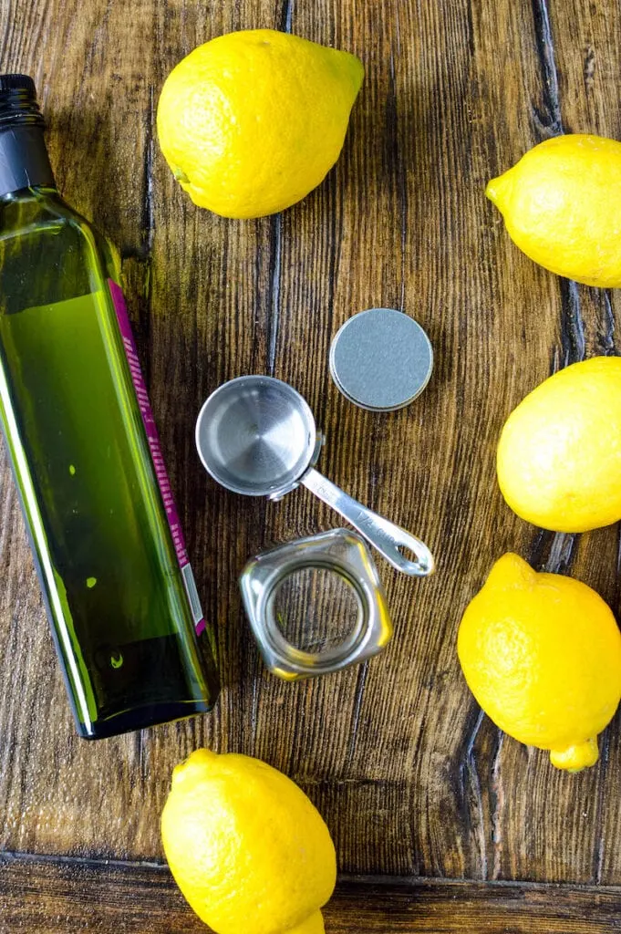 olive oil bottle measuring cups and lemons on wood table