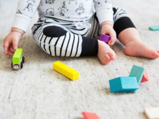baby on carpet playing with colorful blocks