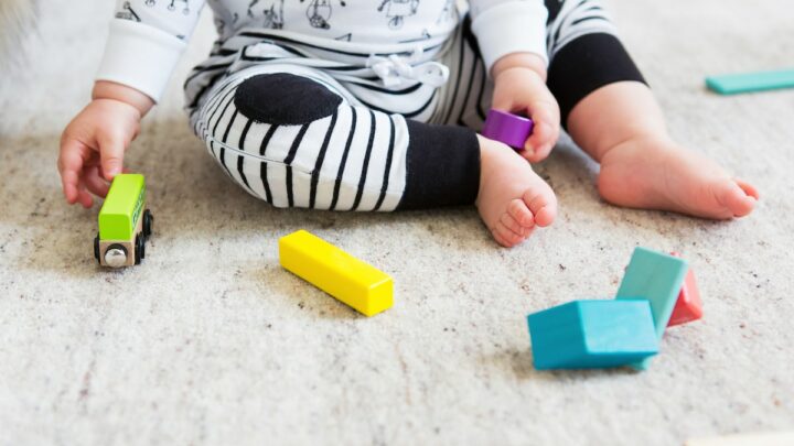 baby on carpet playing with colorful blocks