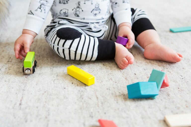 baby on carpet playing with colorful blocks