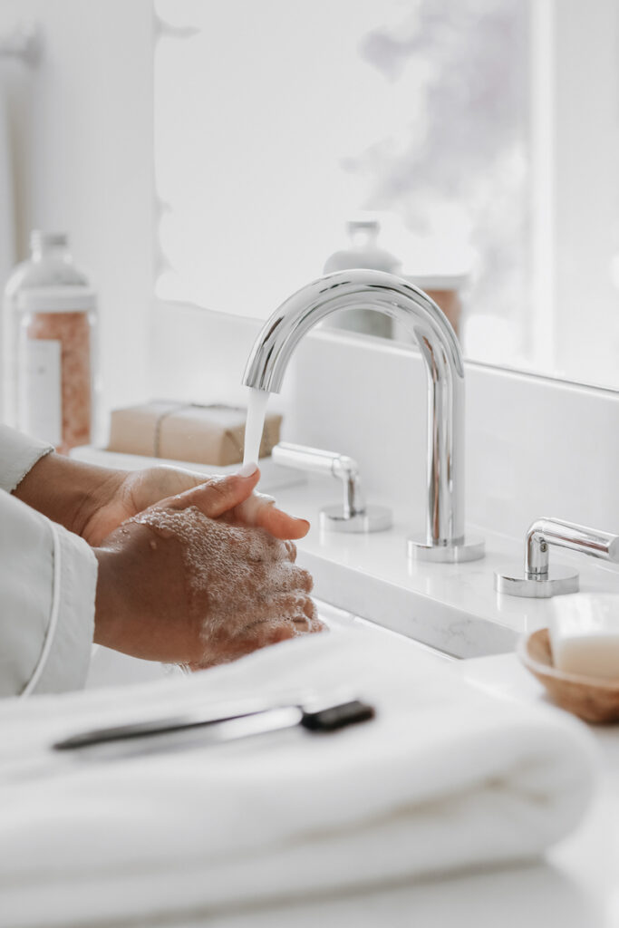 woman washing hands under sink faucet