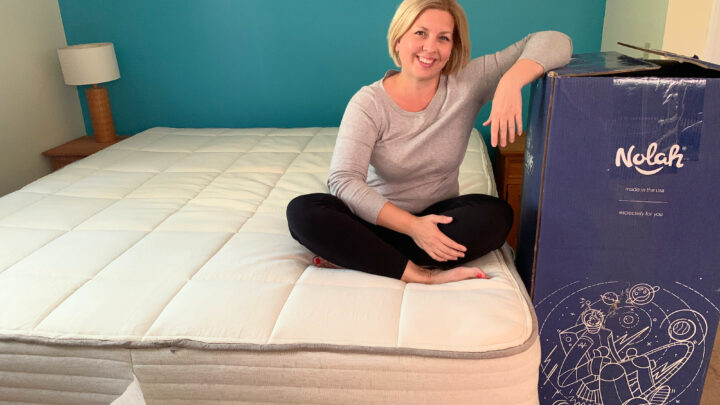 woman sitting on natural mattress with blue shipping box nearby