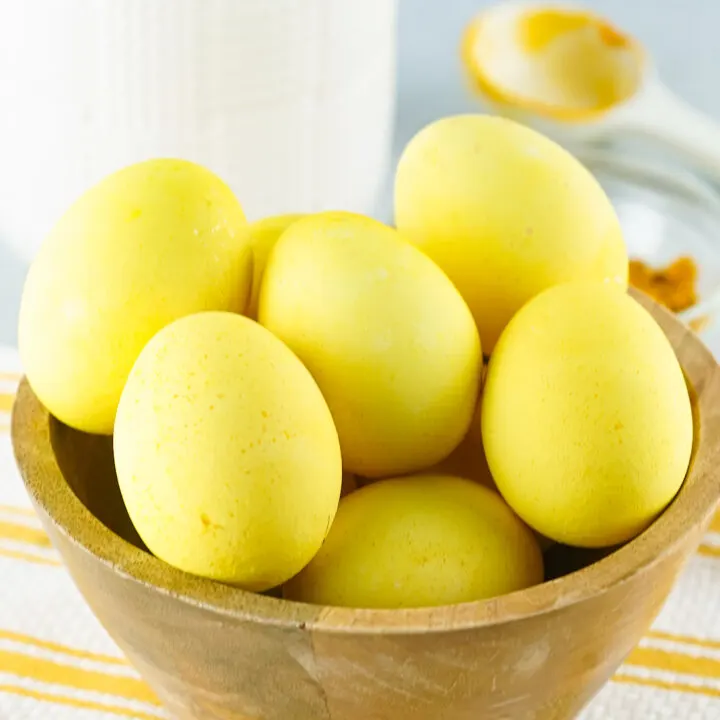 Yellow colored eggs in wooden bowl with white canister in background