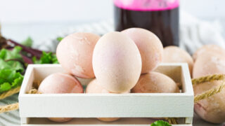 naturally pink dyed eggs in a white crate with jar of beet juice in background