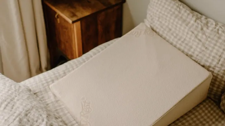 natural latex wedge pillow on a bed with neutral colored bedding