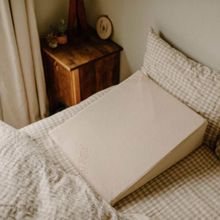 natural latex wedge pillow on a bed with neutral colored bedding