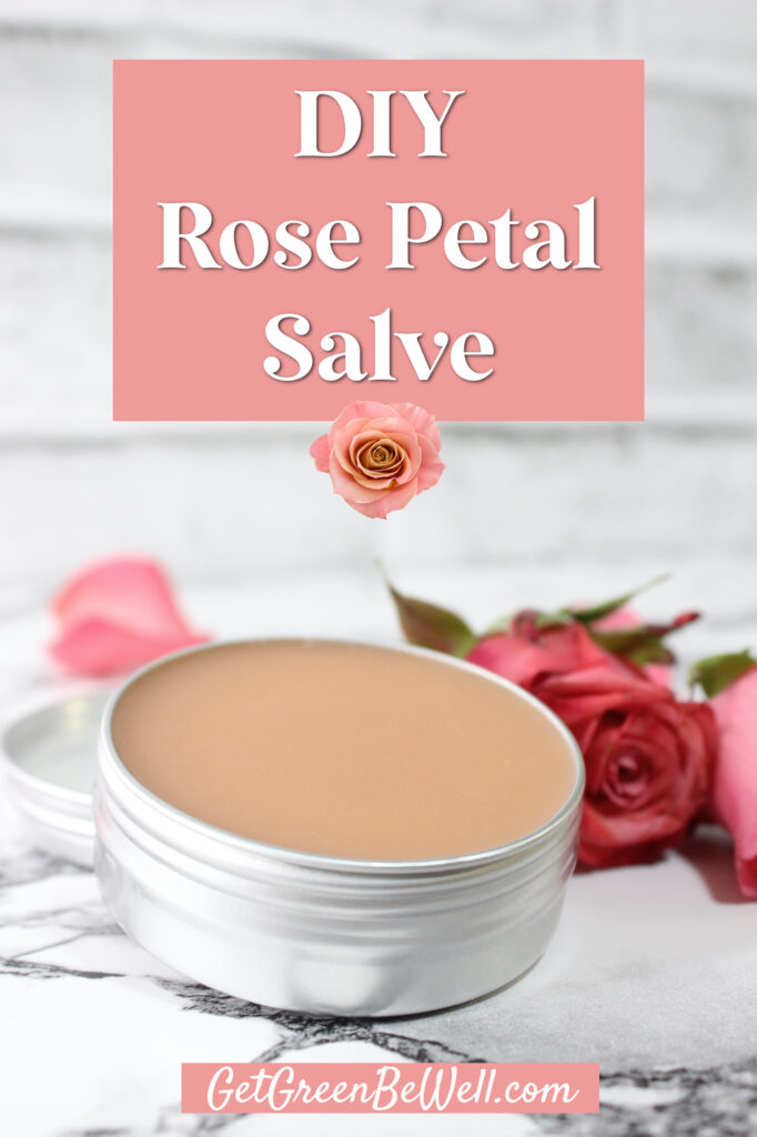 small aluminum tin filled with pink colored rose salve on marble background with fresh rose laying beside it