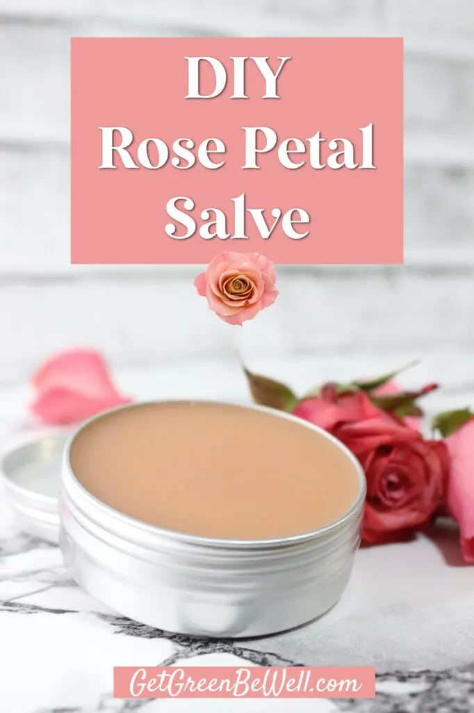 small aluminum tin filled with pink colored rose salve on marble background with fresh rose laying beside it