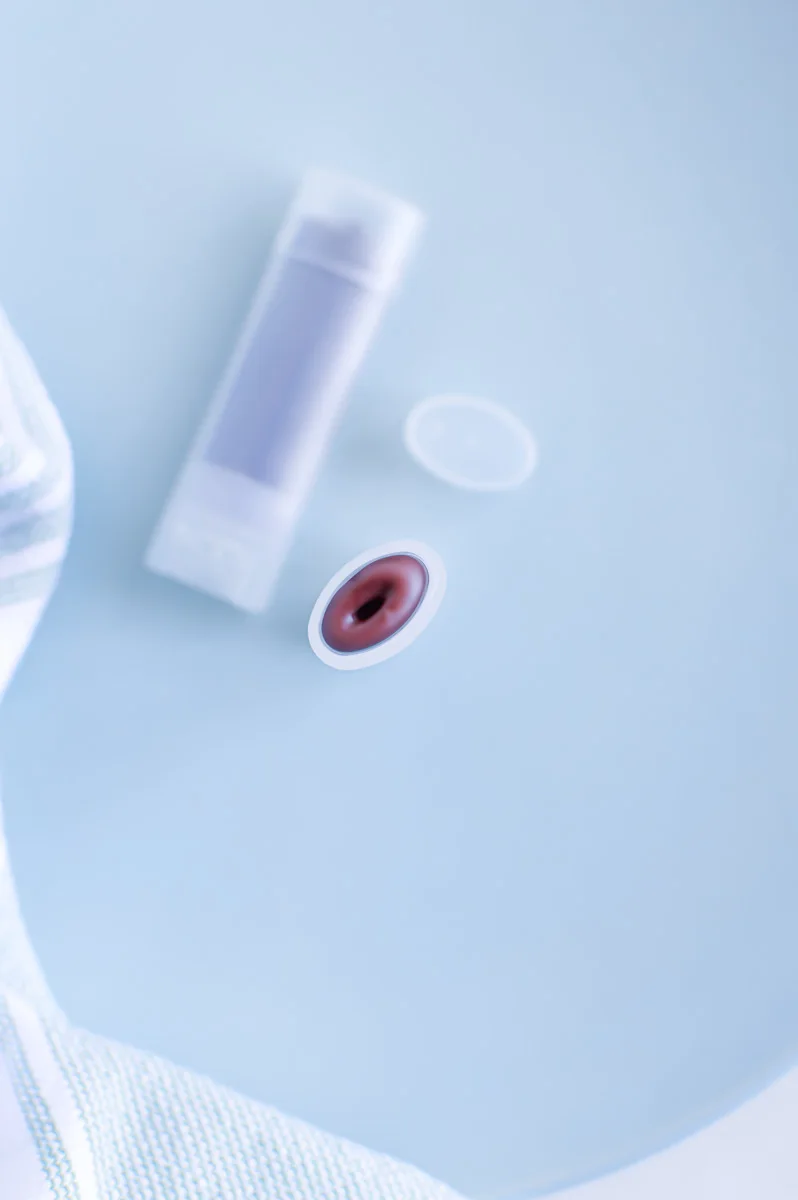 Beetroot Lip Balm in clear tube on light blue colored table top