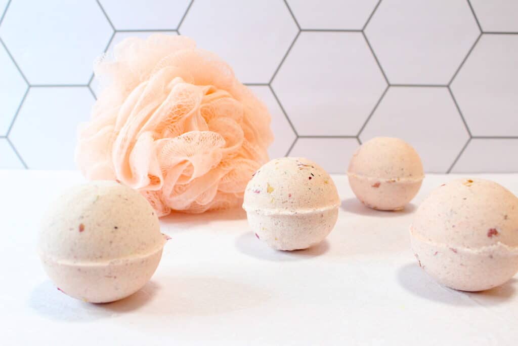 Rose Petal Bath Bomb with shower luffa against white tiles