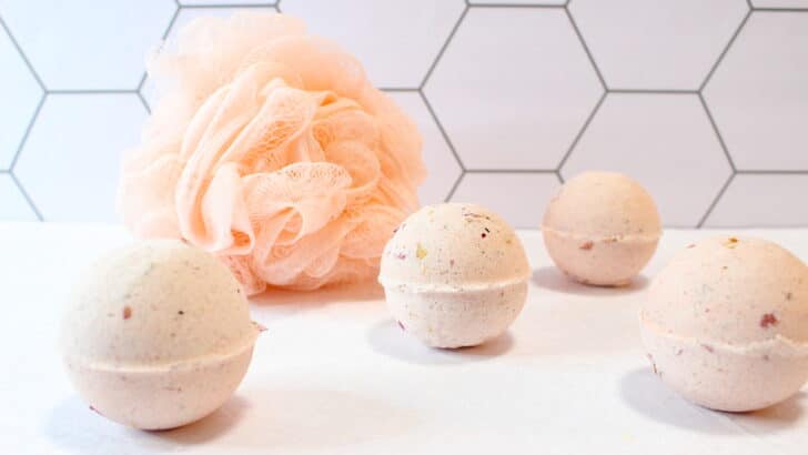 Rose Petal Bath Bomb with shower luffa against white tiles