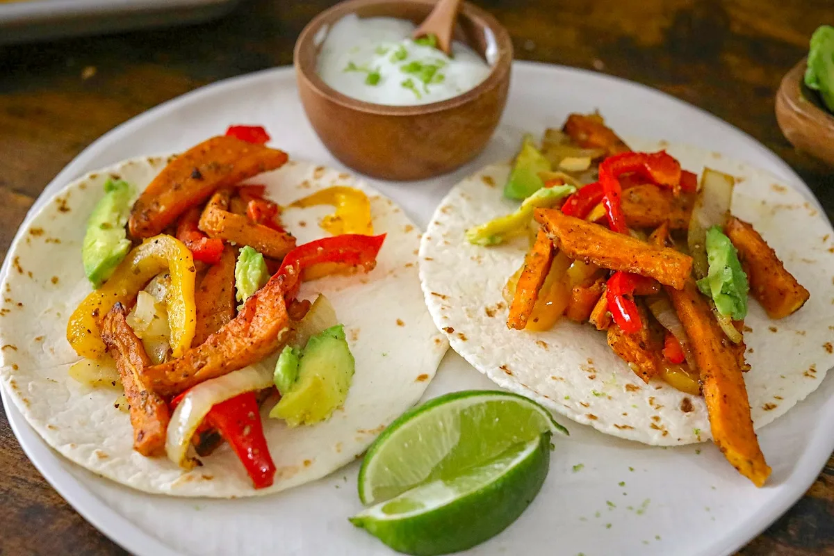Sweet Potato Fajitas on a white plate with a wedge of lime