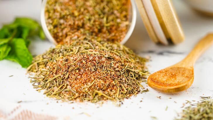 Turkey Rub spilling out of a clear jar onto a table next to a wooden spoon
