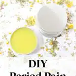 A tin of DIY Cramp Cream, partially opened, surrounded by dried herbs and flowers. Text at the top reads "GetGreenBeWell.com" and at the bottom reads "DIY Period Pain Cream.