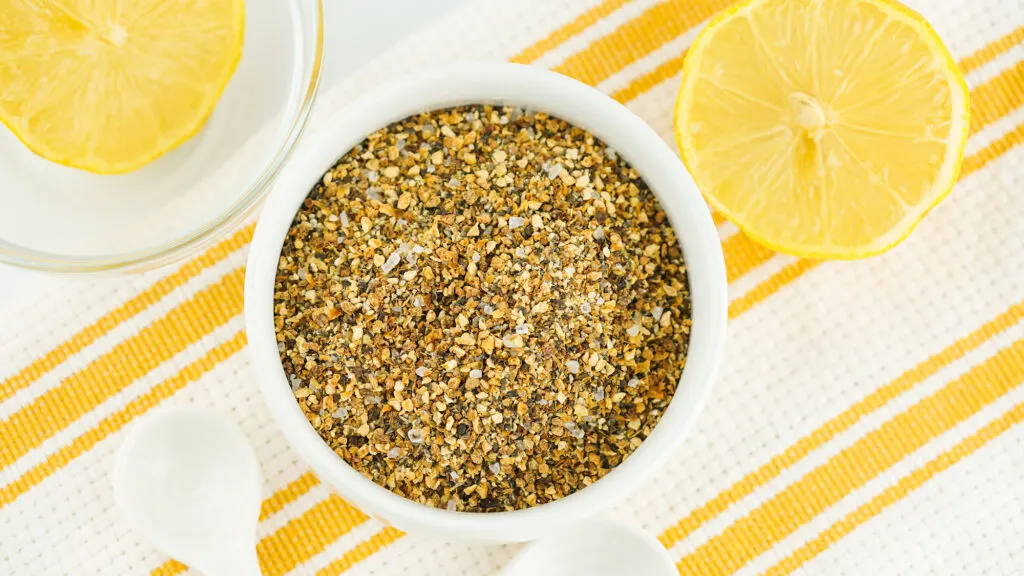 A bowl of homemade lemon pepper seasoning with spoons next to it.
