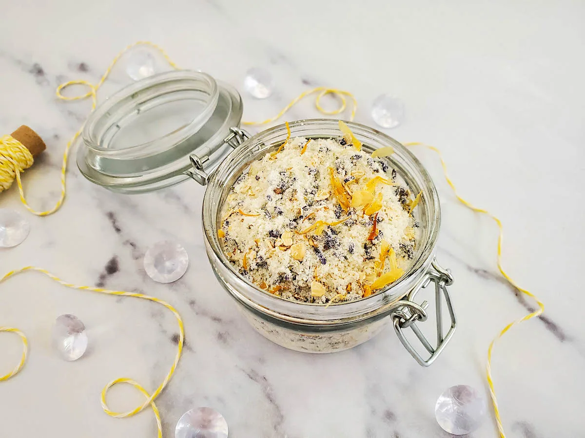 DIY Oatmeal Milk Bath mixture in a glass jar on a white marble table.