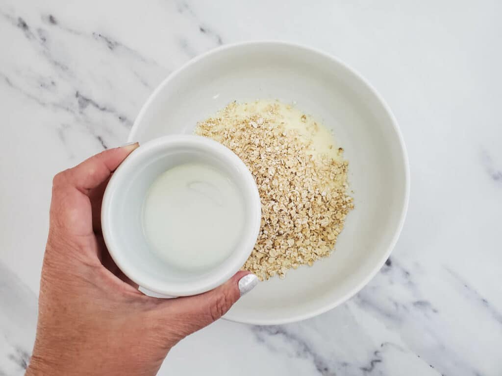 A person holding a bowl of oats and milk.