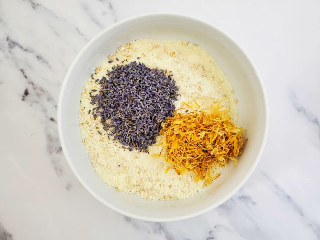 A white bowl with lavender and yellow flowers in it.