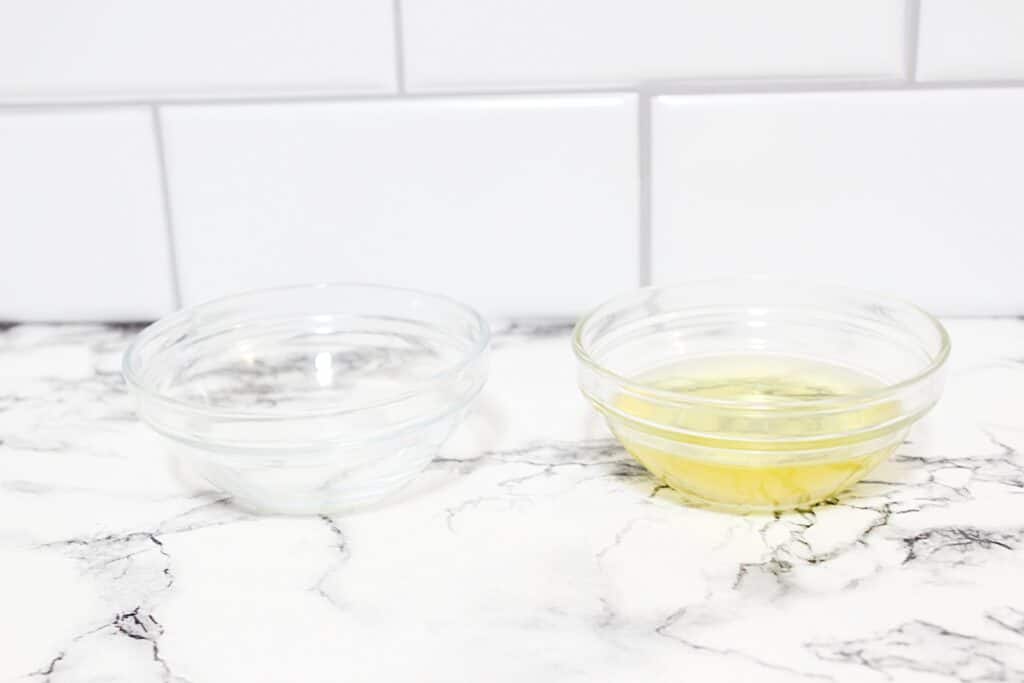 Two bowls of essential oils on a marble counter ingredients for making DIY Vanilla Perfume.