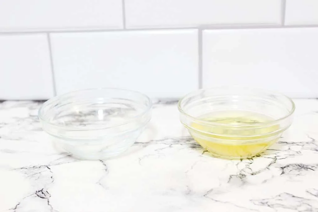 Two bowls of essential oils on a marble counter ingredients for making DIY Vanilla Perfume.