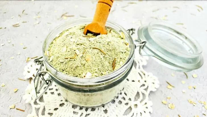 A jar filled with a Detox Clay Bath mixture and a wooden spoon.