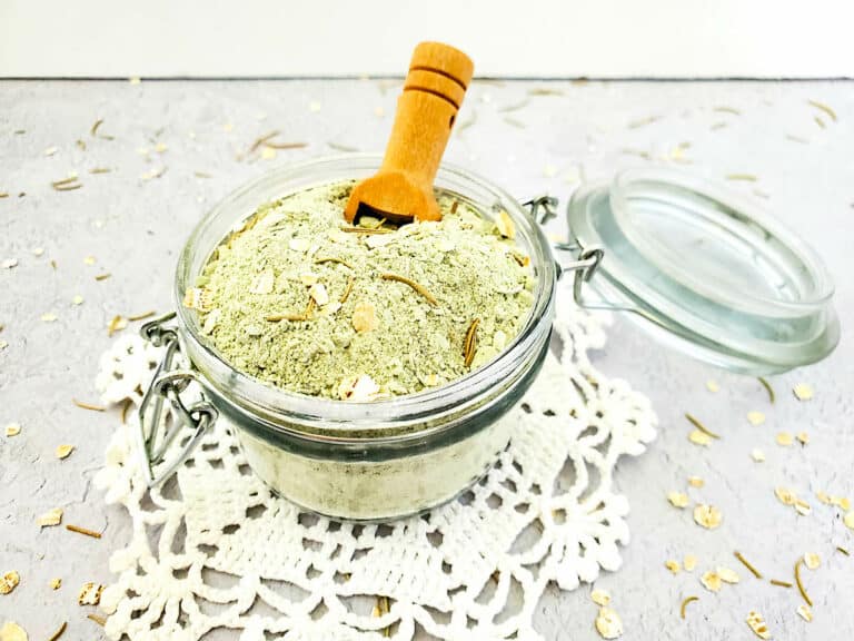 A jar filled with a Detox Clay Bath mixture and a wooden spoon.