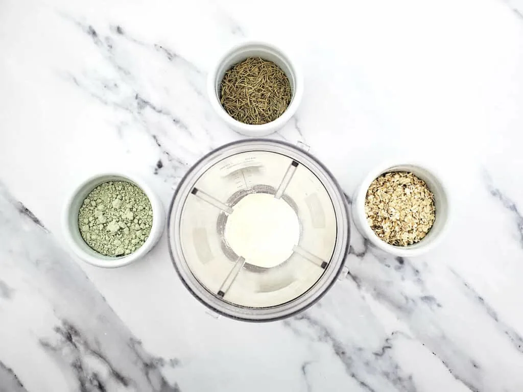 Four bowls of Detox Clay Bath ingredients in a blender on a marble table.