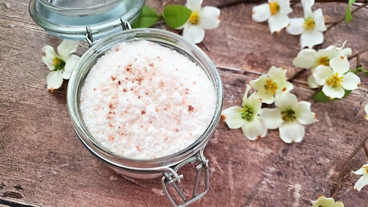 A glass jar with a jar of fizzy bath salts on a wooden table.