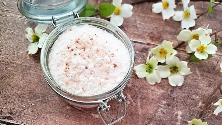 A glass jar with a jar of fizzy bath salts on a wooden table.