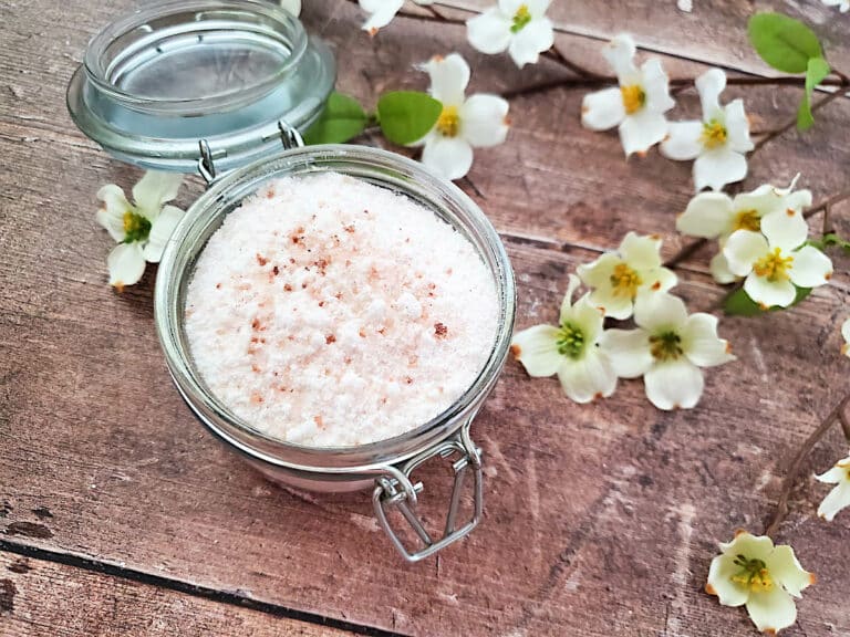 A glass jar with a jar of fizzy bath salts on a wooden table.