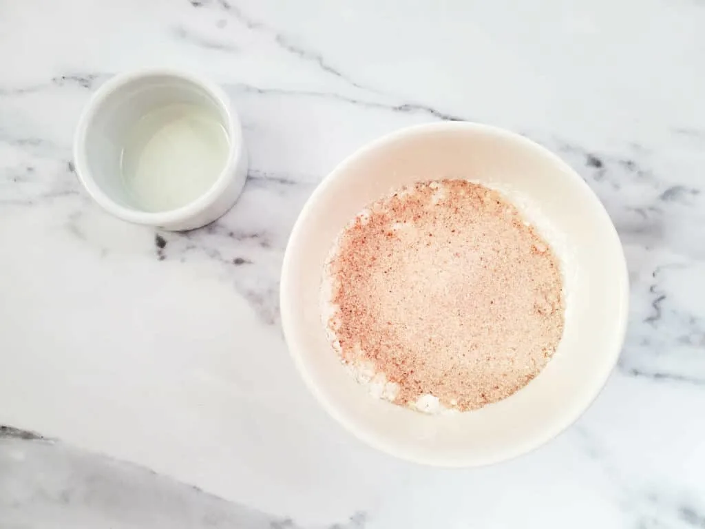 A white bowl with a small amount of powder in it for making fizzy bath salts.