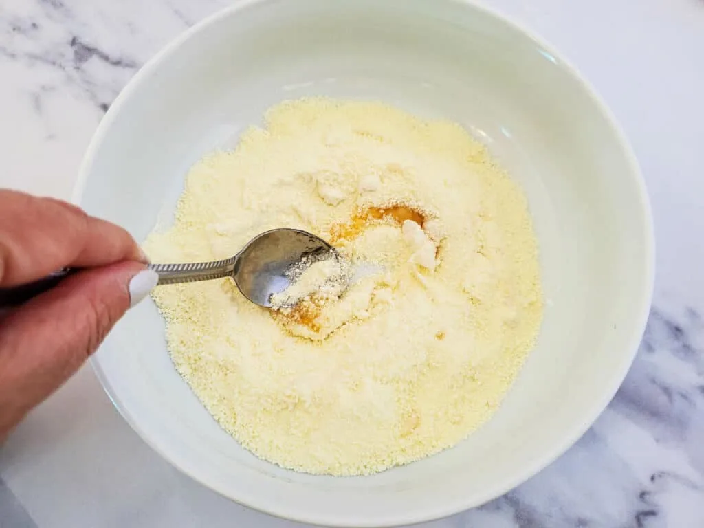 A person pouring milk and honey floral bath soak mixture into a bowl.