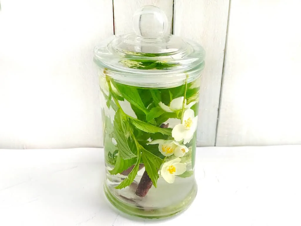 A glass jar filled with water and flowers to make Moon Water.