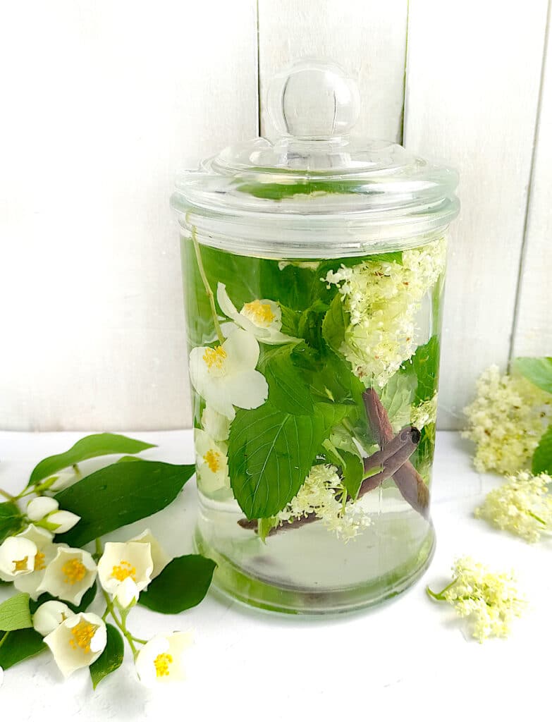 A glass jar with fragrant flowers and cinnamon sticks to be used as Moon Water.