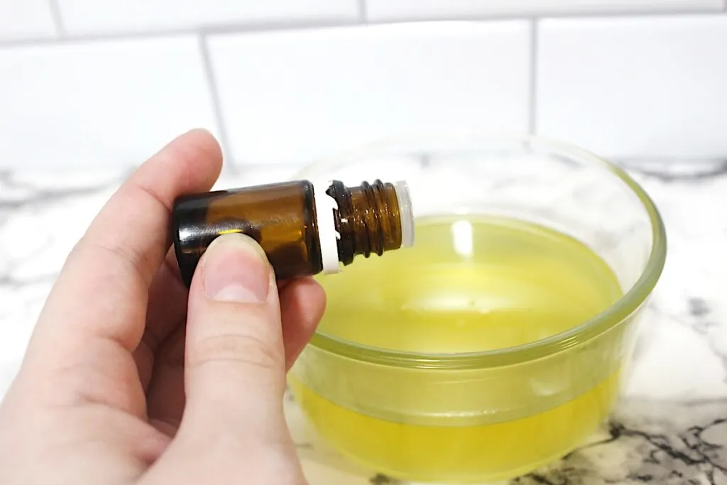 Rosemary Salve Step 2 A person holding a bottle of essential oil in a bowl.