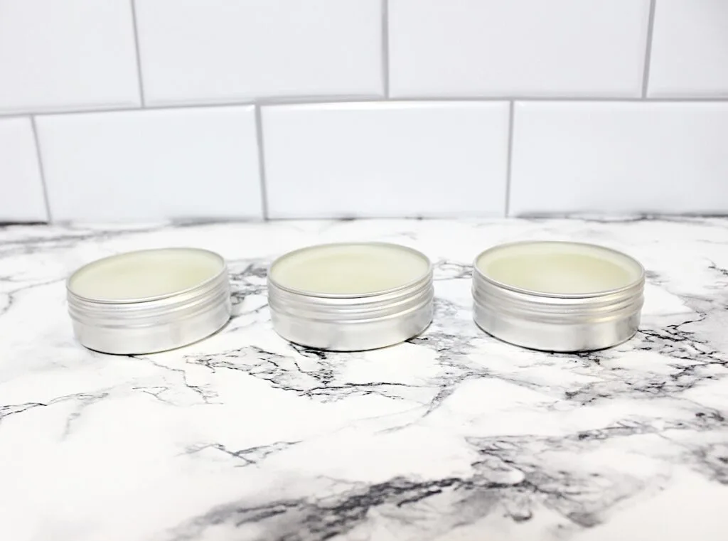 Rosemary Salve Step 4 with three tins of lip balm sitting on a marble counter.