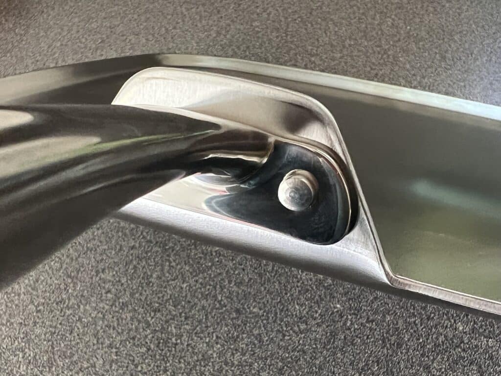 A close up of a metal handle on a 360 cookware table.