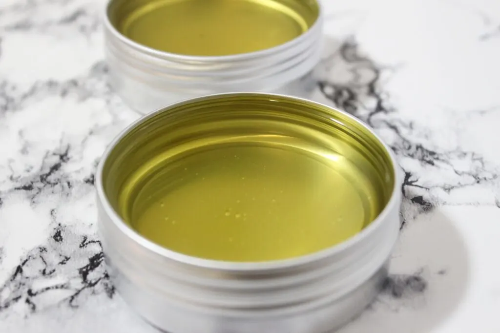 Two tins of rosemary-infused olive oil on a marble table.