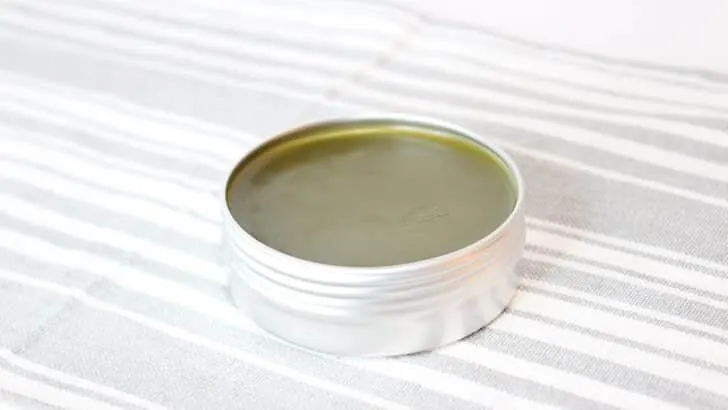 Comfrey Salve in a metal tin a striped towel.