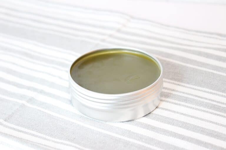 Comfrey Salve in a metal tin a striped towel.