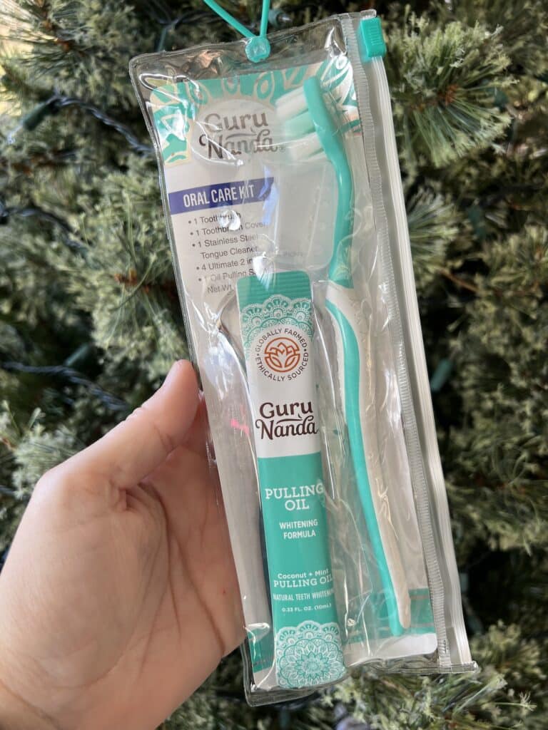 A person holding a toothbrush in front of a Christmas tree, emphasizing the importance of healthy dental habits during the holiday season.