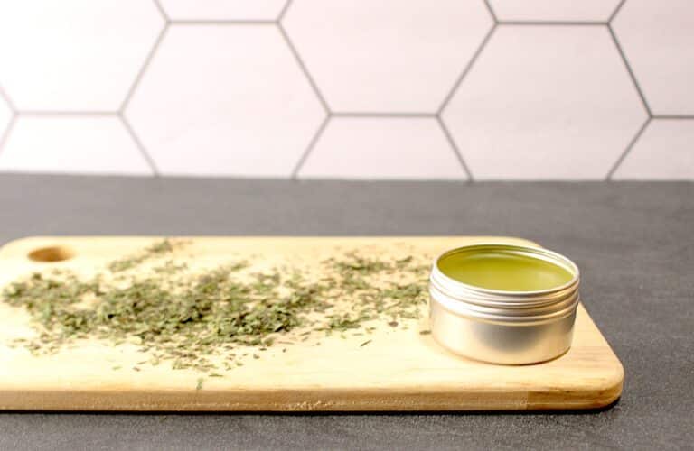 A tin of Plantain Salve on a cutting board.