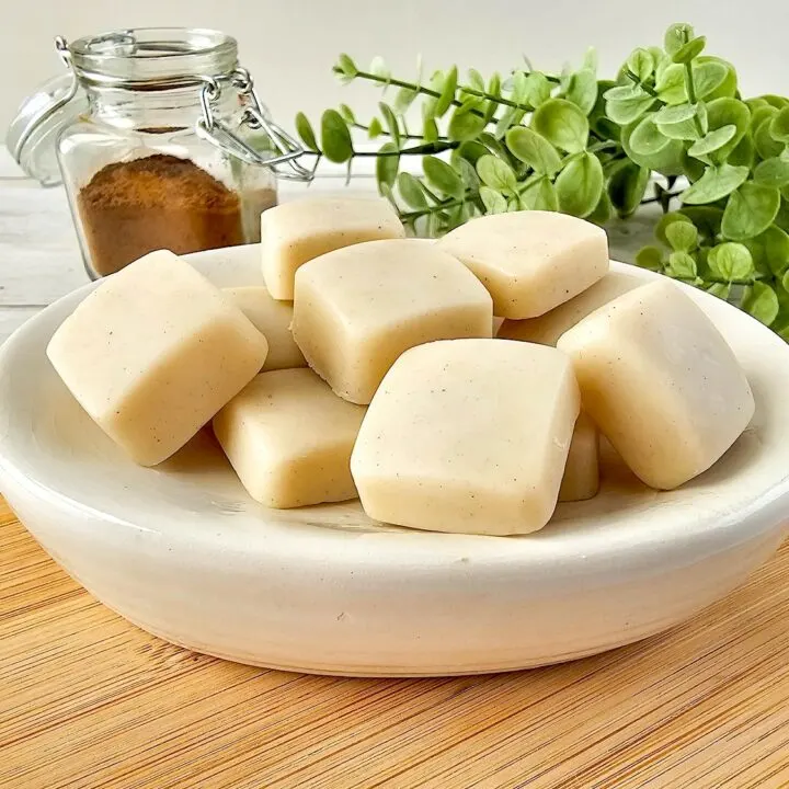 Vanilla Homemade Lotion Bar - A bowl of soap cubes on a wooden cutting board.