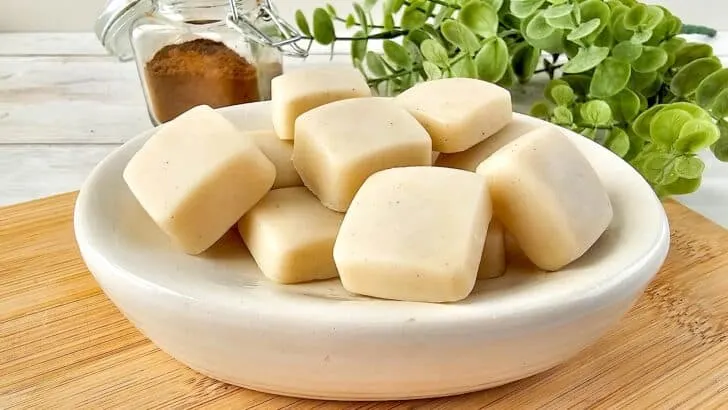 Vanilla Homemade Lotion Bar - A bowl of soap cubes on a wooden cutting board.