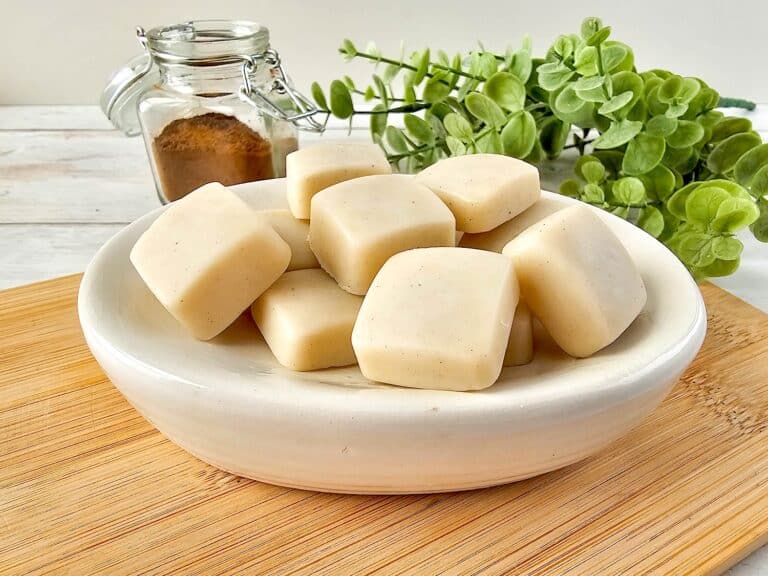 Vanilla Homemade Lotion Bar - A bowl of soap cubes on a wooden cutting board.