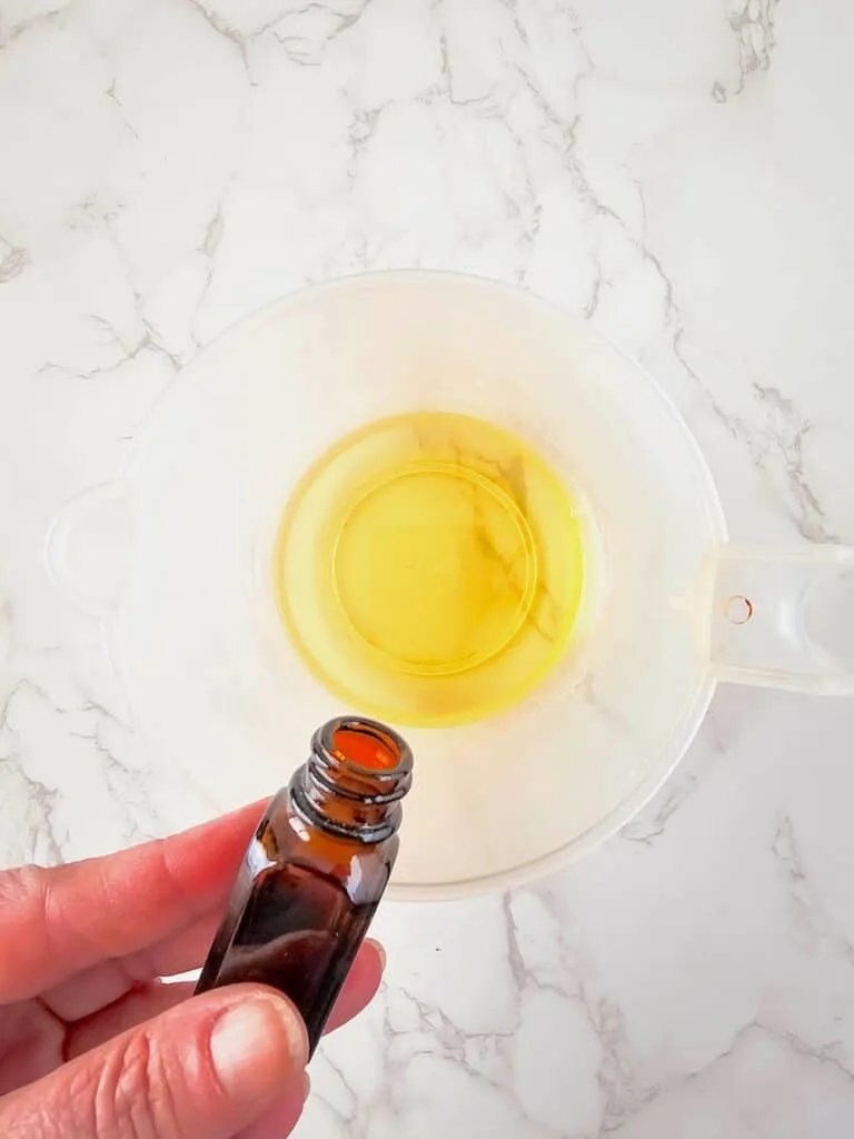 Vanilla Homemade Lotion Bar Step 3 - A person holding an essential oil in a bowl.