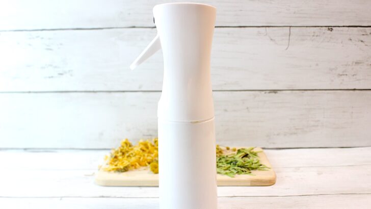 A white bottle of Jewelweed Spray on top of a wooden cutting board.