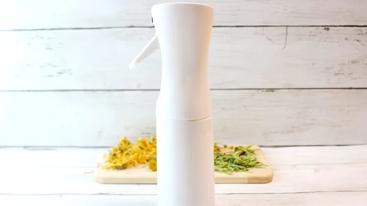 A white bottle of Jewelweed Spray on top of a wooden cutting board.