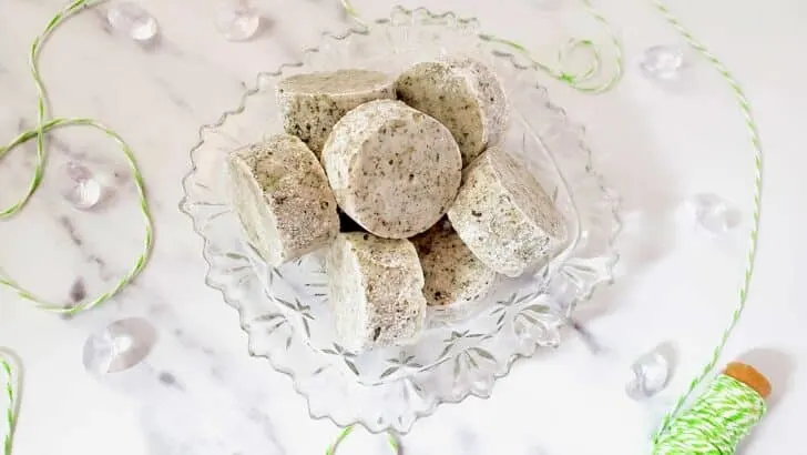 Peppermint Shower Steamers in a clear decorative bowl on a white marble surface.