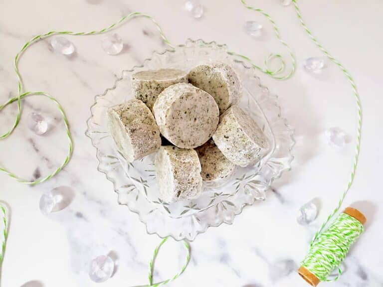 Peppermint Shower Steamers in a clear decorative bowl on a white marble surface.